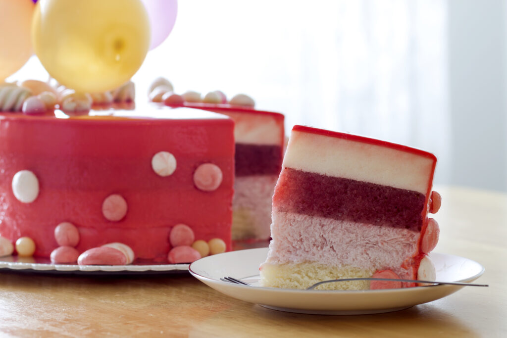 Homemade red birthday cake with air baloons. Slice of a red velvet cake on a plate.