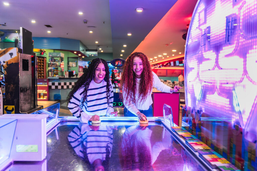 Two female friends playing air hokey in an arcade