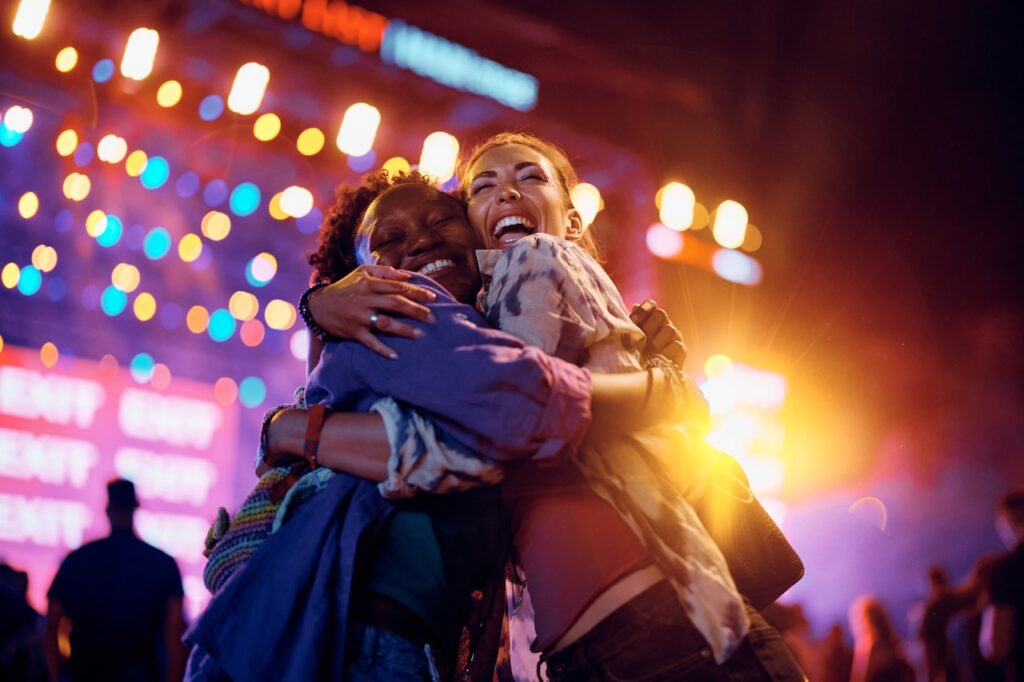 cheerful female friends embracing at a music festival